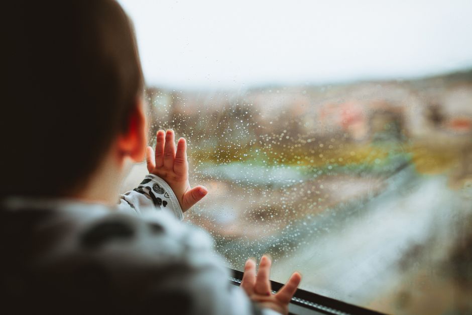 Bé nhìn ra ngoài cửa sổ khi trời mưa