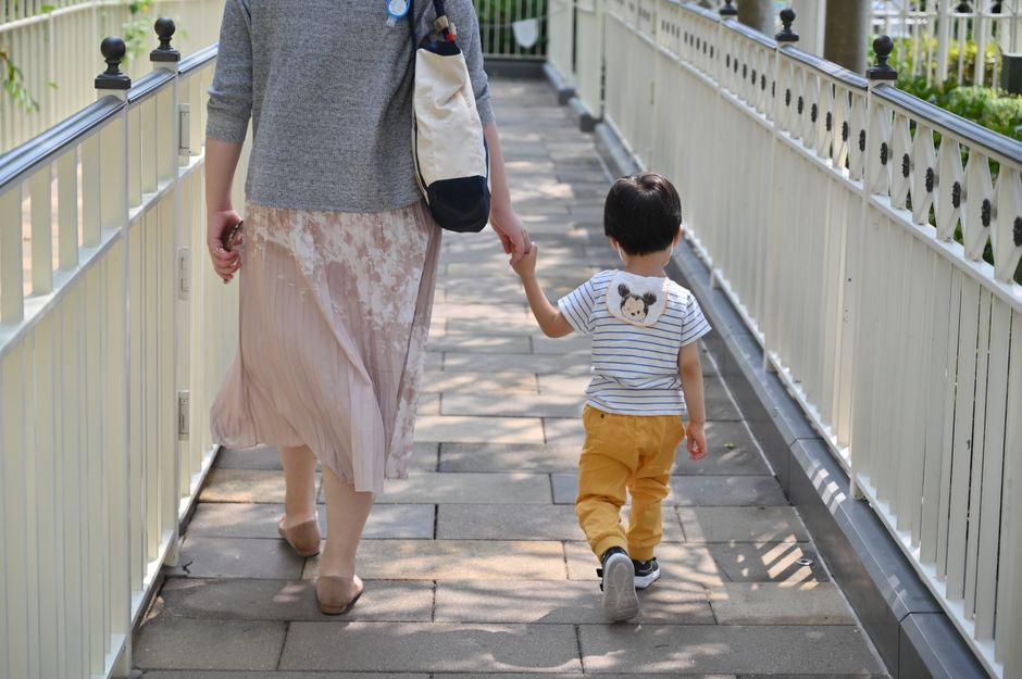 Mẹ dắt tay bé đi bộ trên phố